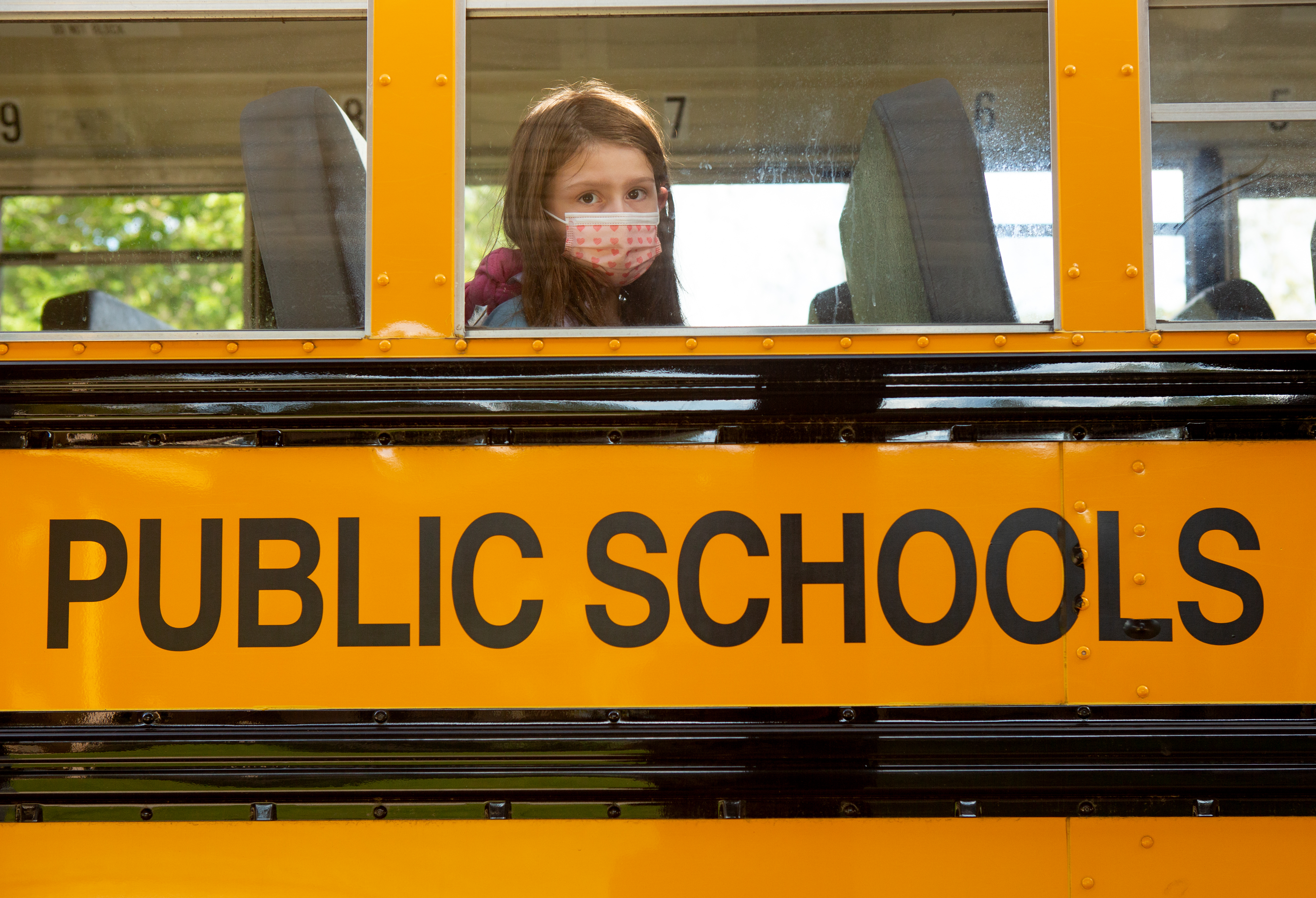 Girl with covid mask sits on a public school bus